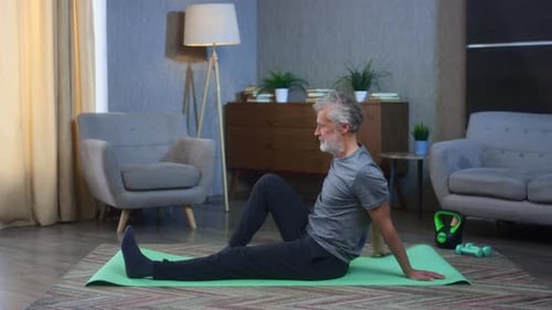 Mature Adult Stretching on Yoga Mat at Home