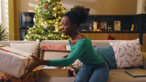 Woman Organizes Christmas Gifts at Home on Couch