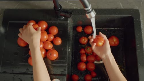 Washing fresh tomatoes in the kitchen sink for meal preparation