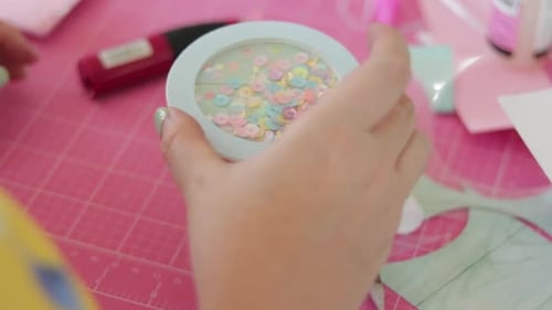 Female hand moves cute sequin shaker, are of various pastel colors