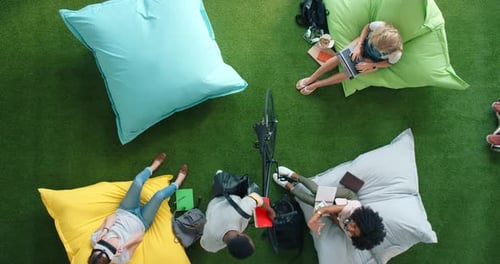 Above view of creative businesspeople relaxing and working on bean bags in an informal office setup