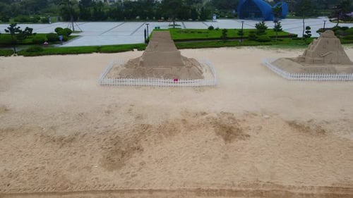 Beach sand pyramids with different themes etched on sand sculptures with green natural garden backgr