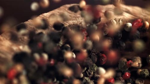 Colorful Peppercorns Falling into Wooden Bowl