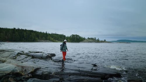 Active Leisure In Nature Lonely Woman With Backpack Standing On Shore Of Lake In Cloudy Weather