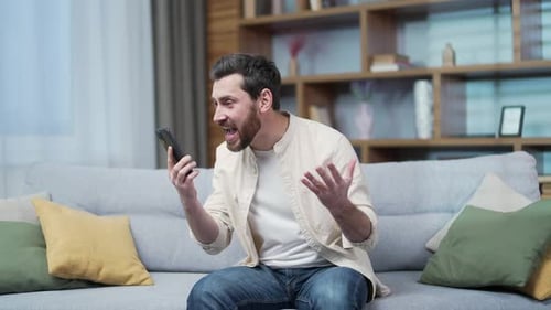 Angry Man Talking on Smartphone Indoors