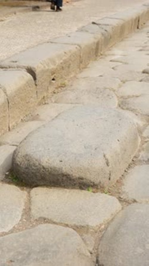 Vertical close-up of a large stepping stone on a Pompeii street, with worn Roman paving and raised