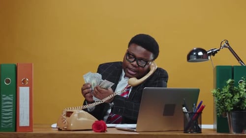 A Young Professional Engaged in a Thoughtful Phone Conversation at a Modern Office Desk