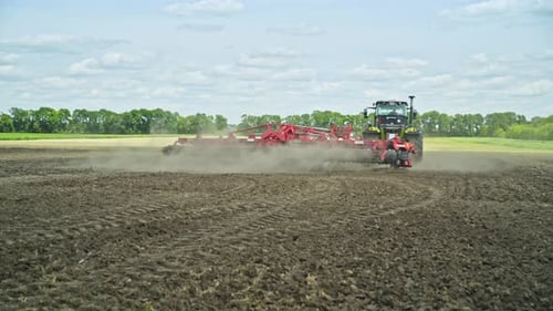 Agricultural tractor plowing a vast field in a rural farming landscape