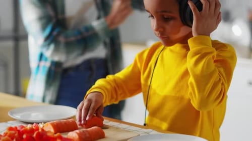 Boy with Headphones Prepares Vegetables in Bright Kitchen