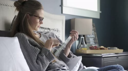 Woman Using Tablet Device in Bed at Home