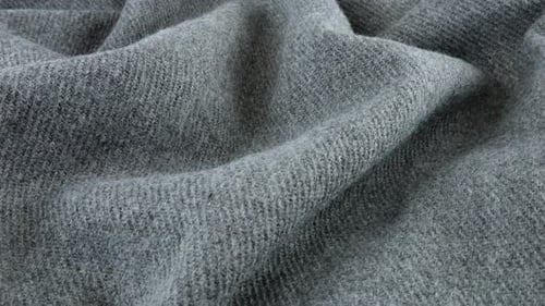 Top view of the soft folds of textured gray wool fabric rotated on the display case