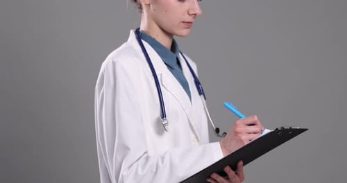 Medical assistant with clipboard on grey background, closeup