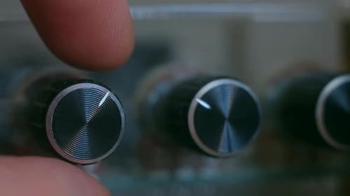Finger Adjusting Settings on Audio Equipment Knobs