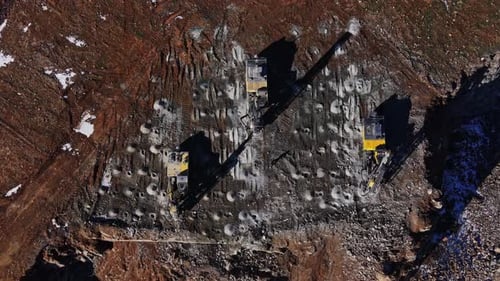 Construction work is taking place at a site with machinery on rocky ground