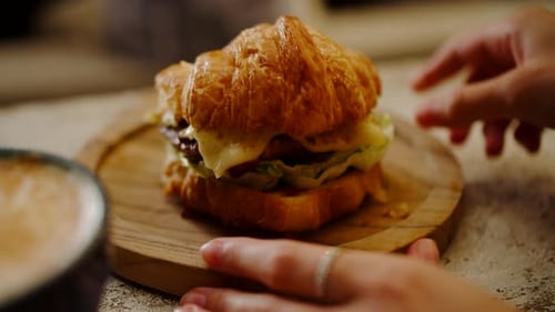 Woman's Hands Twisting a Wooden Croissant Plate Breakfast in a Cafe