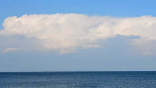 Moving of Large White Cumulus Rain Clouds in Blue Sky Over Blue Sea on Sunny Day