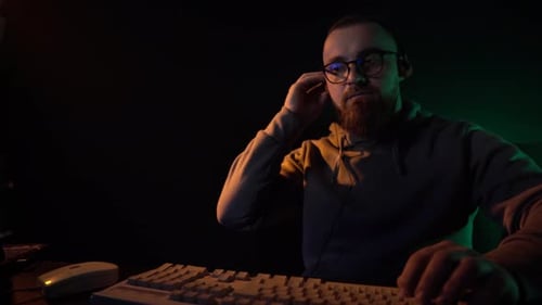 Man Typing at Computer in Darkly Lit Room