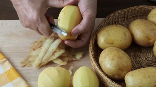 Hands Peeling Potato With Vegetable Peeler