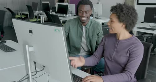 Two Young Adult Engineers in Office Looking at Computer Code