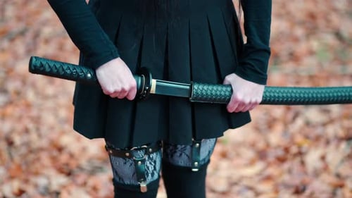 Young girl in a black skirt with garters and stockings pulls out a katana sword. Preparing for battl