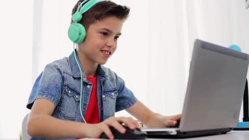 Der junge hispanische Junge spielt gerne zu Hause mit Kopfhörern auf seinem Laptop