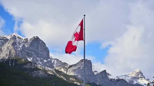 Canadian Flag Waving Against Snow Capped Mountains