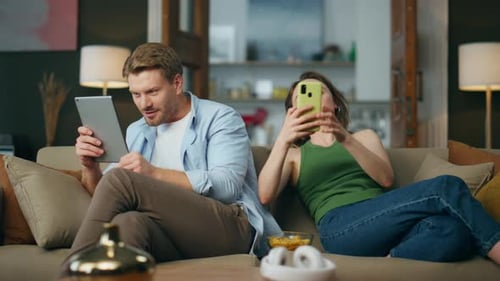 Couple relaxing at home using digital devices