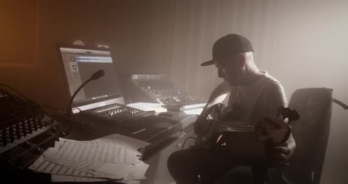 Male Music Composer Playing Bass Guitar in Studio