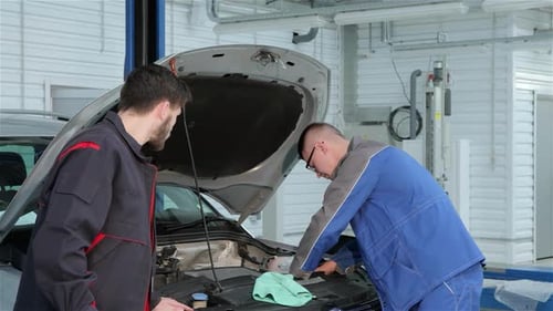 Un jeune mécanicien résout des problèmes de voiture avec un partenaire spécialisé à la station-service