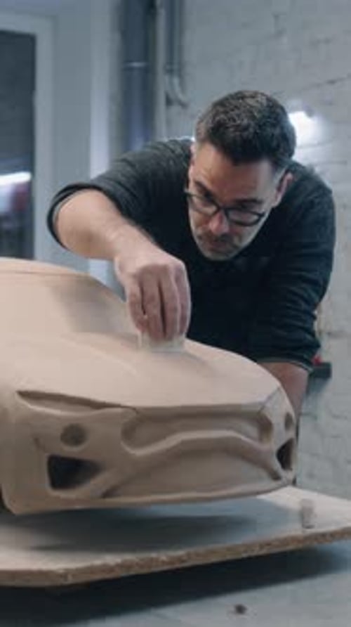 Un designer automobile sculpte le prototype de la voiture à l'aide d'outils de sculpture