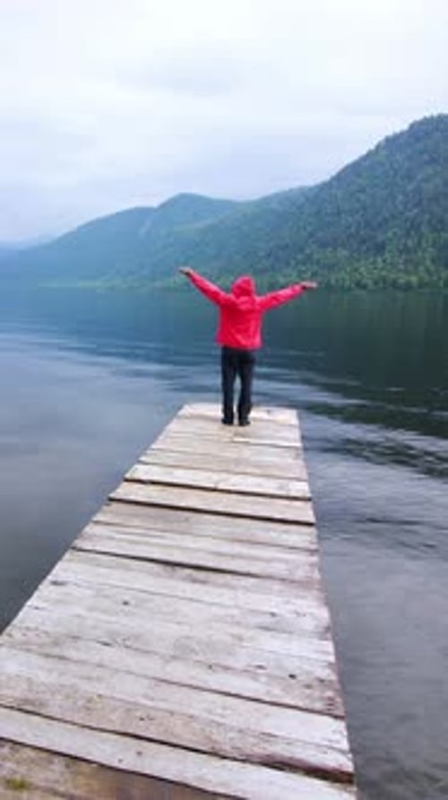 Walking Alone on a Wooden Dock By a Tranquil Lake Surrounded By Mountains in Cool Weather