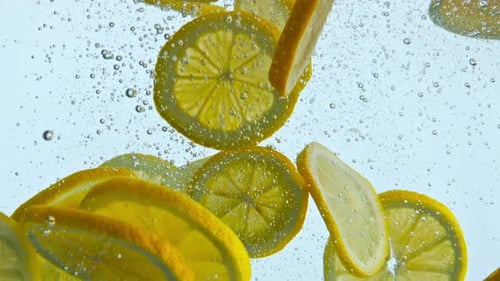 Cut Juicy Lemon Floating in Crystal Water with Air Bubbles Close Up