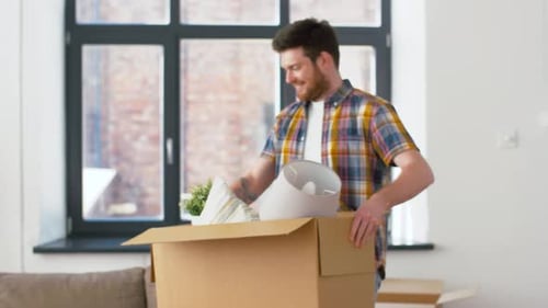 Moving, People And Real Estate Concept - Happy Man With Box At New Home