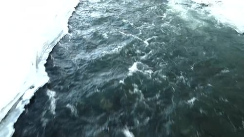 Frozen River Flows Through Snowy Winter Landscape