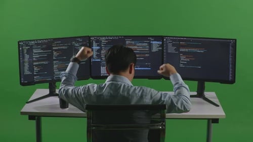 Happy Asian Man Celebrating And Dancing While Write Code With Multiple Computer In Green Screen