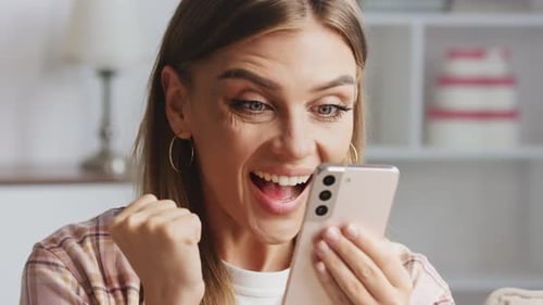 Woman Looks At Phone and Reacts With Joy