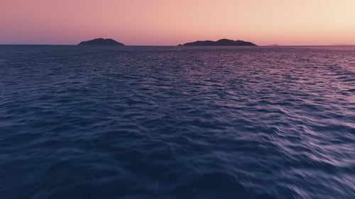 Low altitude flight over the sea surface with waves during sunset time