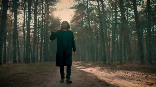 Killer Wearing Coat and Wig in Forest Man with Axe in Hands Spooky Murderer Slowly Walking Through