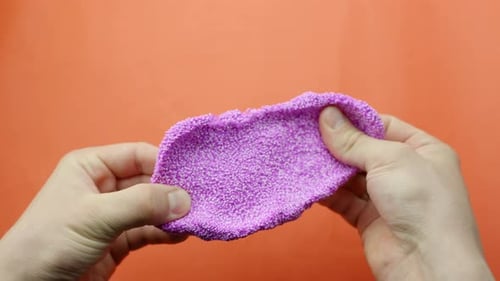 Pulling Stretchy Pink Floam Slime Against Bold Red Background