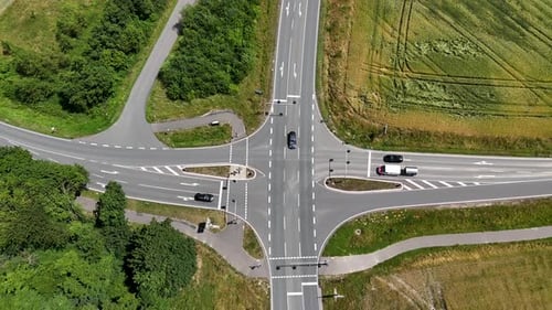 Junction with cars in suburb of American town. Green grass fields in rural area. Aerial top down ris