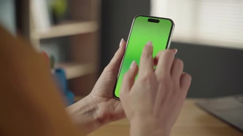 Person Holding a Mobile Phone with a Chroma Key Green Screen Interacting with the Touchscreen