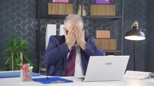 Stressed Businessman Working At Desk On Laptop