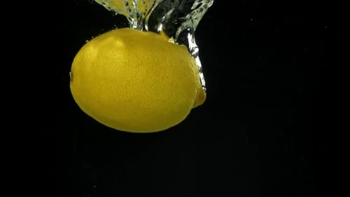 Citrons tombant sous l'eau sur fond noir filmés par une caméra haute vitesse à 1000 images par seconde