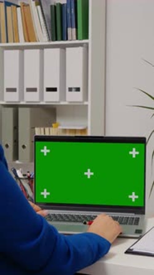 Vertical Screen Woman sitting working on laptop with green screen display