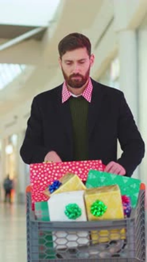 Man with Gifts in Shopping Cart at Mall