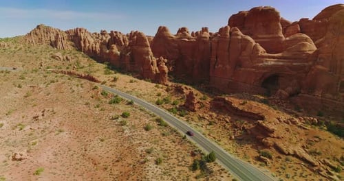 Car Driving through Desert Road Surrounded by Rock Formations