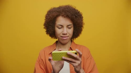 Adult Using a Mobile Phone on Yellow Background