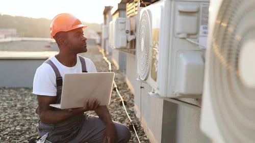 HVAC Technician Inspecting Air Conditioners on Rooftop
