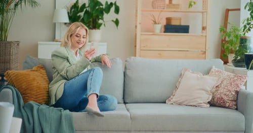 Young Woman Relaxing on Couch Using Smartphone