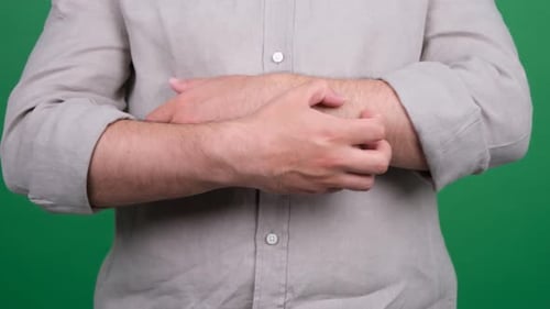 Adult Man vigorously scratching an arm on green screen